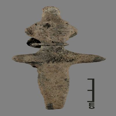 Figurine. Anthropomorphic figure with small conical hat, two holes for earrings, one earring remaining, neck torque, arms spread, lower body ending like a peg. Bronze.; YPM BC 031116