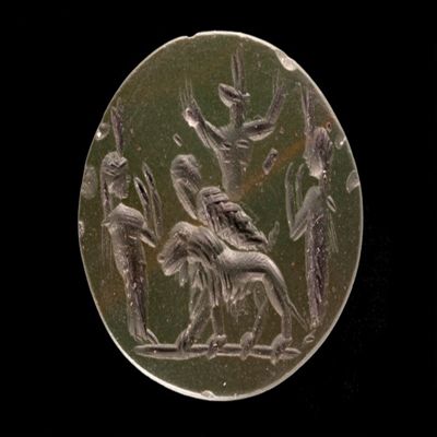 Amulet. Ob. Mummy on lion walking left; Anubis in background with hands raised; flanked by two goddesses with hands raised. Rev: bibioy? / 17 vowels/ iao. Number of lines: three. Green jasper.; YPM BC 038177