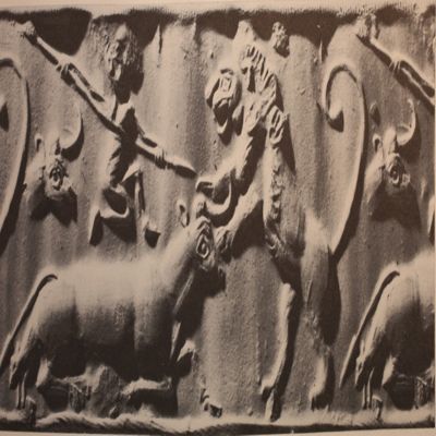 Cylinder seal. Bull's head, warrior, over back of cow giving birth, spearing rampant lion. Uruk IV. Serpentine.; YPM BC 037592
