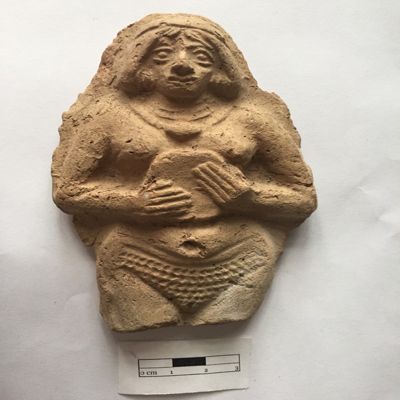 Figurine, single mold. Female holding tambourine in both hands, wearing headband, multi-strand necklace, earrings with three hoops, lines across lower belly. Large stippled public area. Facial details, fingers, navel and vulva clearly indicated. Old Babylonian. Terracotta.; YPM BC 023977