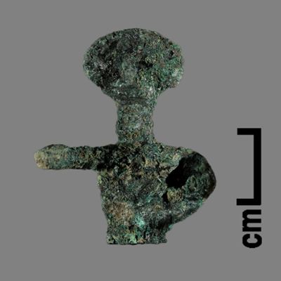 Figurine. Anthropomorphic figure, circular flat head, right arm spread out, left arm in cup handle shape against flank, lower body ending like a peg. Bronze.; YPM BC 031152