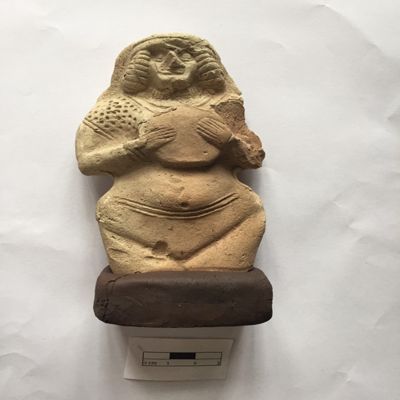 Figurine, single mold. Female holding tambourine, wearing double headband, double necklace, dotted shawl across both shoulders. Three lines across belly above pelvic area. Facial details, fingers, navel and vulva clearly indicated. Old Babylonian. Clay.; YPM BC 023976