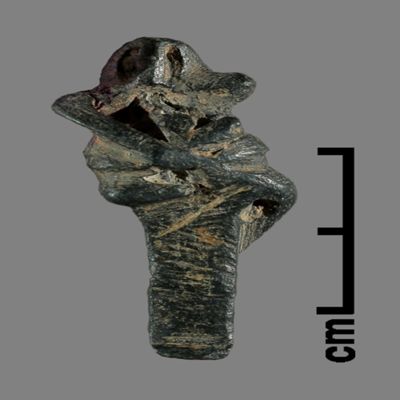Figurine. Anthropomorphic figure clasping large unidentified object to its chest, legs and feet joined in flat lower body. Bronze.; YPM BC 031154